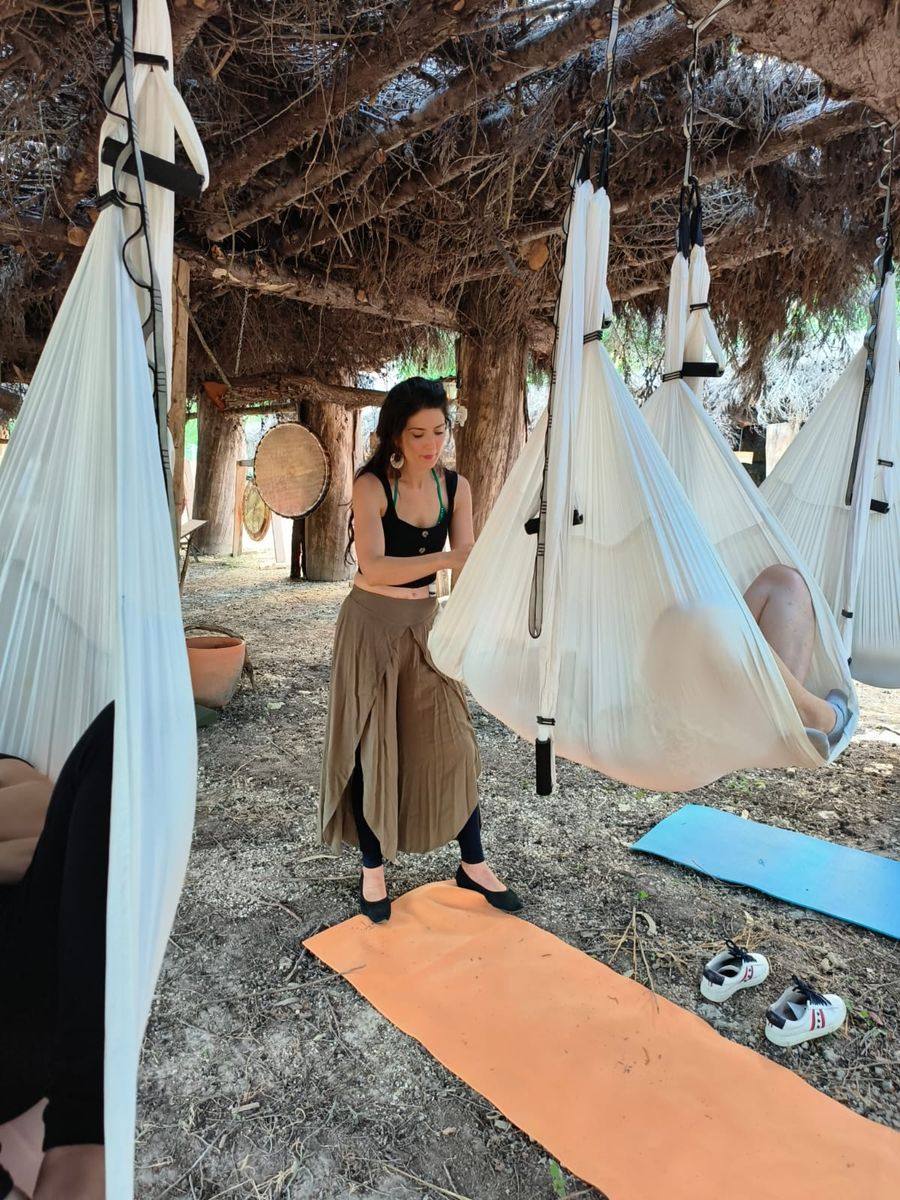 Professora a ajustar um tecido sob uma cabana de madeira, ao ar livre