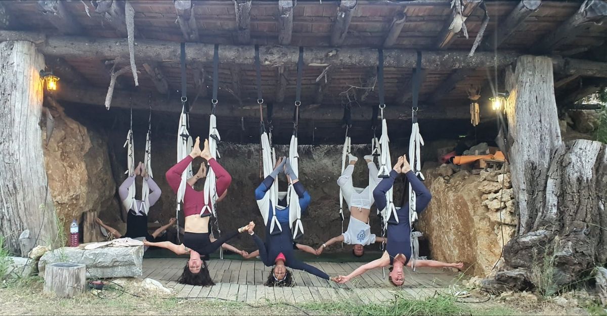 Grupo em inversão nos tecidos sob um alpendre de madeira, de mãos dadas
